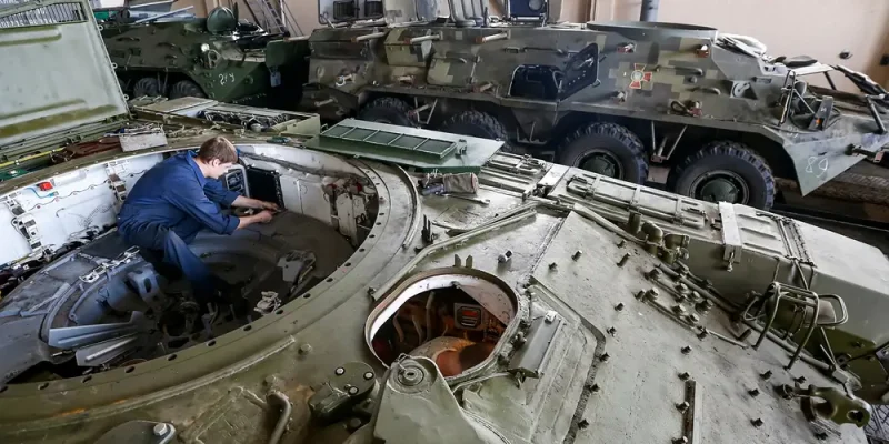 Un mécanicien en tenue de travail effectue une opération de maintenance à l’intérieur d’un véhicule blindé, illustrant la spécialité Auto Engins Blindés du CSTAGN, dédiée à l’entretien et à la réparation des véhicules de la gendarmerie, du parc automobile aux engins blindés.